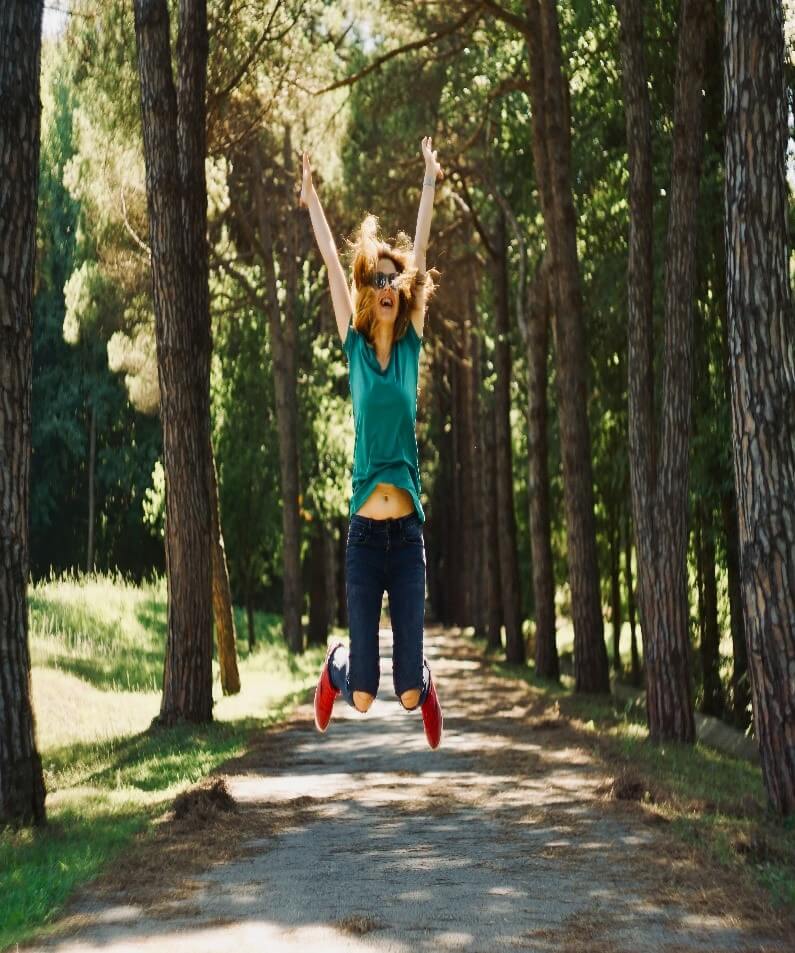 Happy woman jumping in the forest